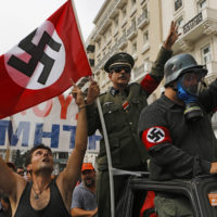 File picture shows demonstrators dressed as Nazis and waving a swastika flag as they ride in an open-top car in Syntagma Square in Athens as they protest against the visit of Germany's Chancellor Angela Merkel
