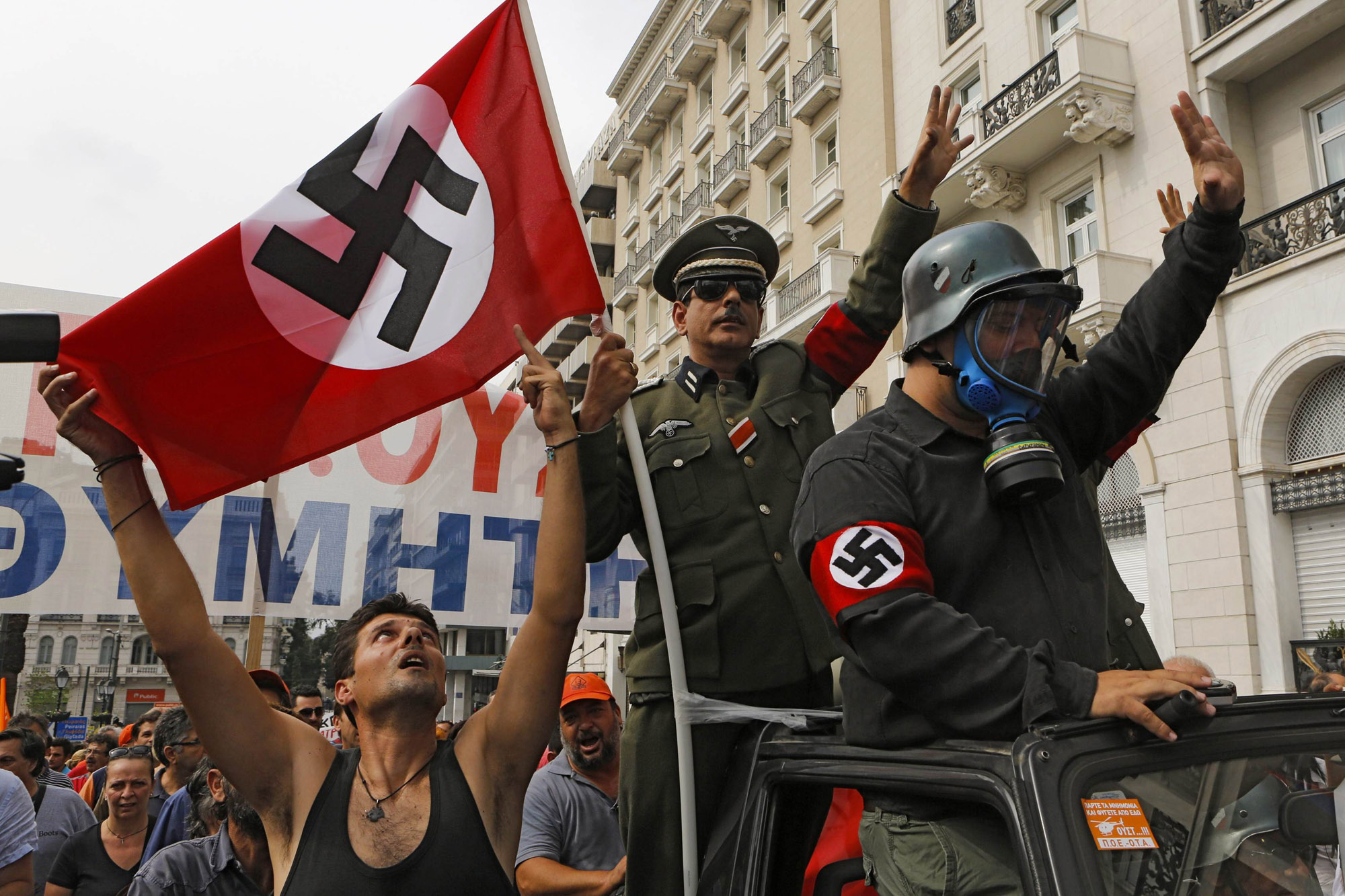 File picture shows demonstrators dressed as Nazis and waving a swastika flag as they ride in an open-top car in Syntagma Square in Athens as they protest against the visit of Germany's Chancellor Angela Merkel